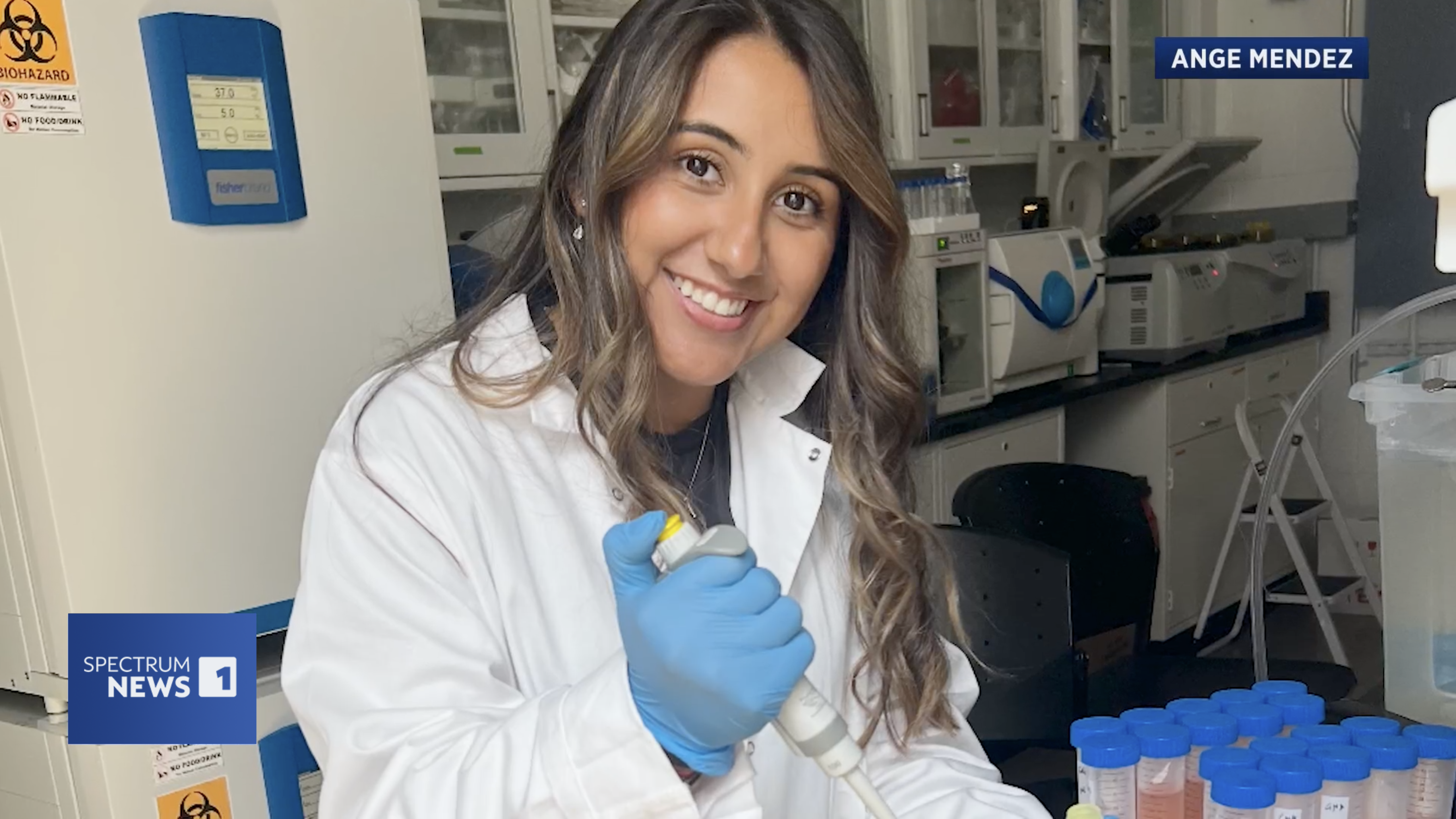 Ange Mendez in the lab wearing a white lab coat and gloves